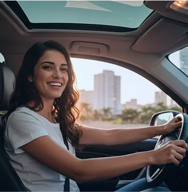 Mulher segurando o volante de seu carro, sorrindo enquanto olha para o lado
